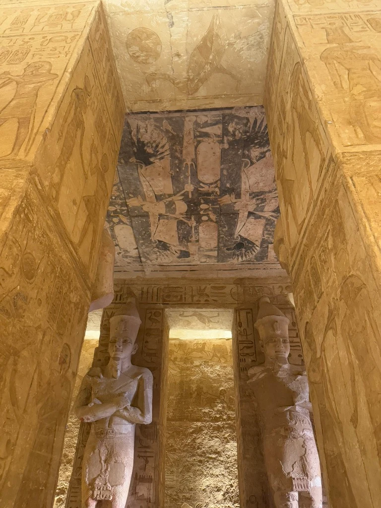 Intérieur du temple Abou Simbel avec les statues immenses et les murs décorés visibles.