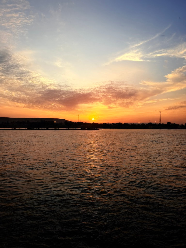Coucher de soleil orangé face à l'étendue d'eau du Nil