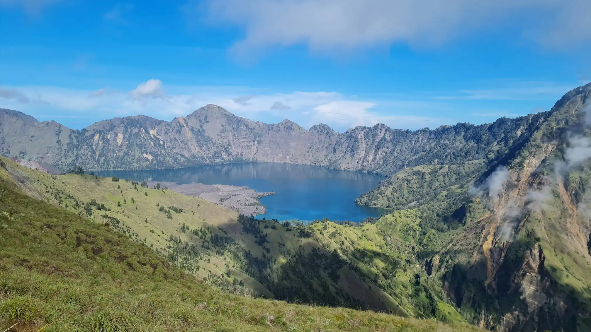 Mont Rinjani avec une vallée verdoyante en premier plan et le lac du cratère en fond