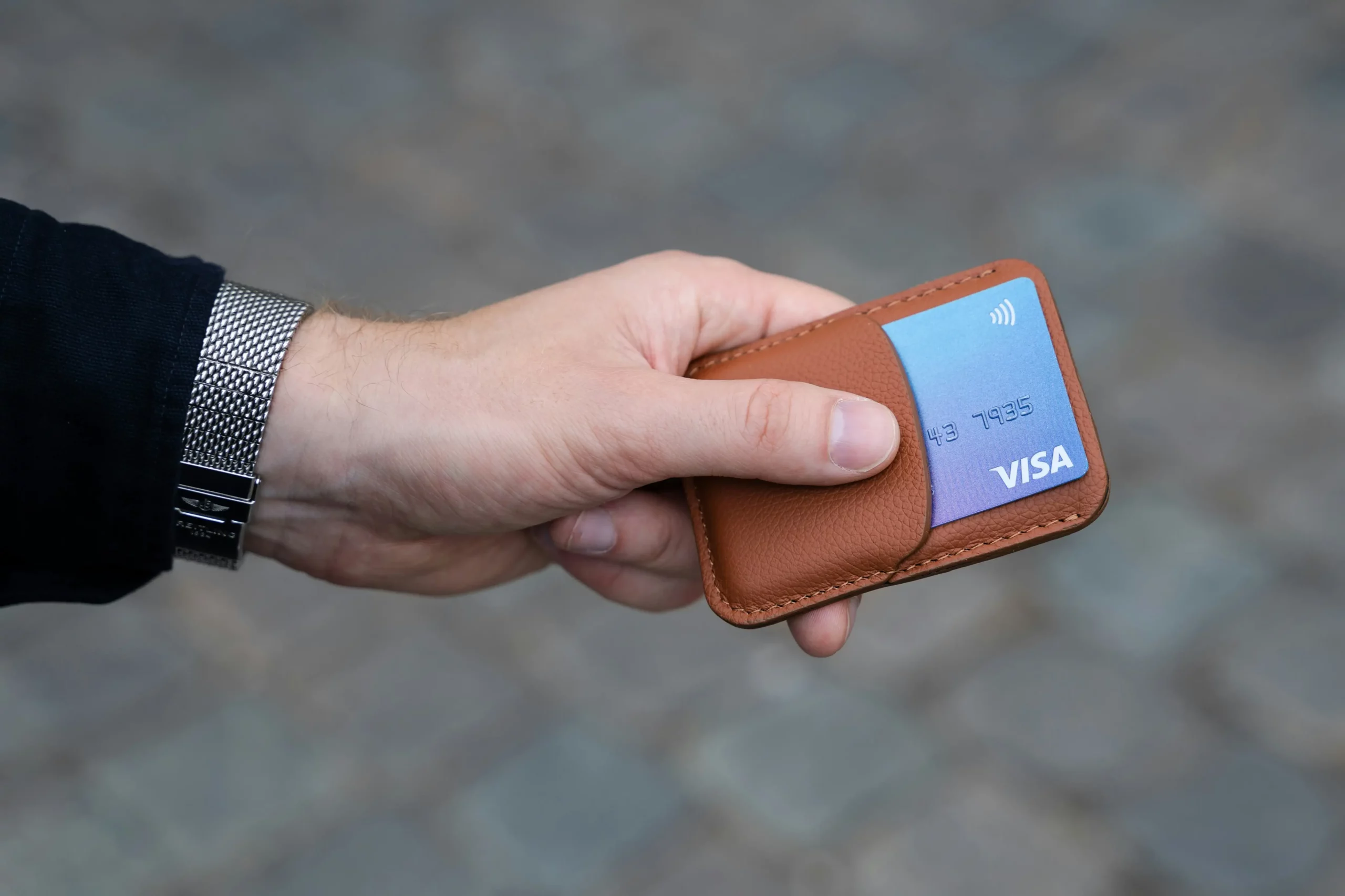 Main tenant un porte-carte avec une carte bancaire visa bleue à l'intérieur