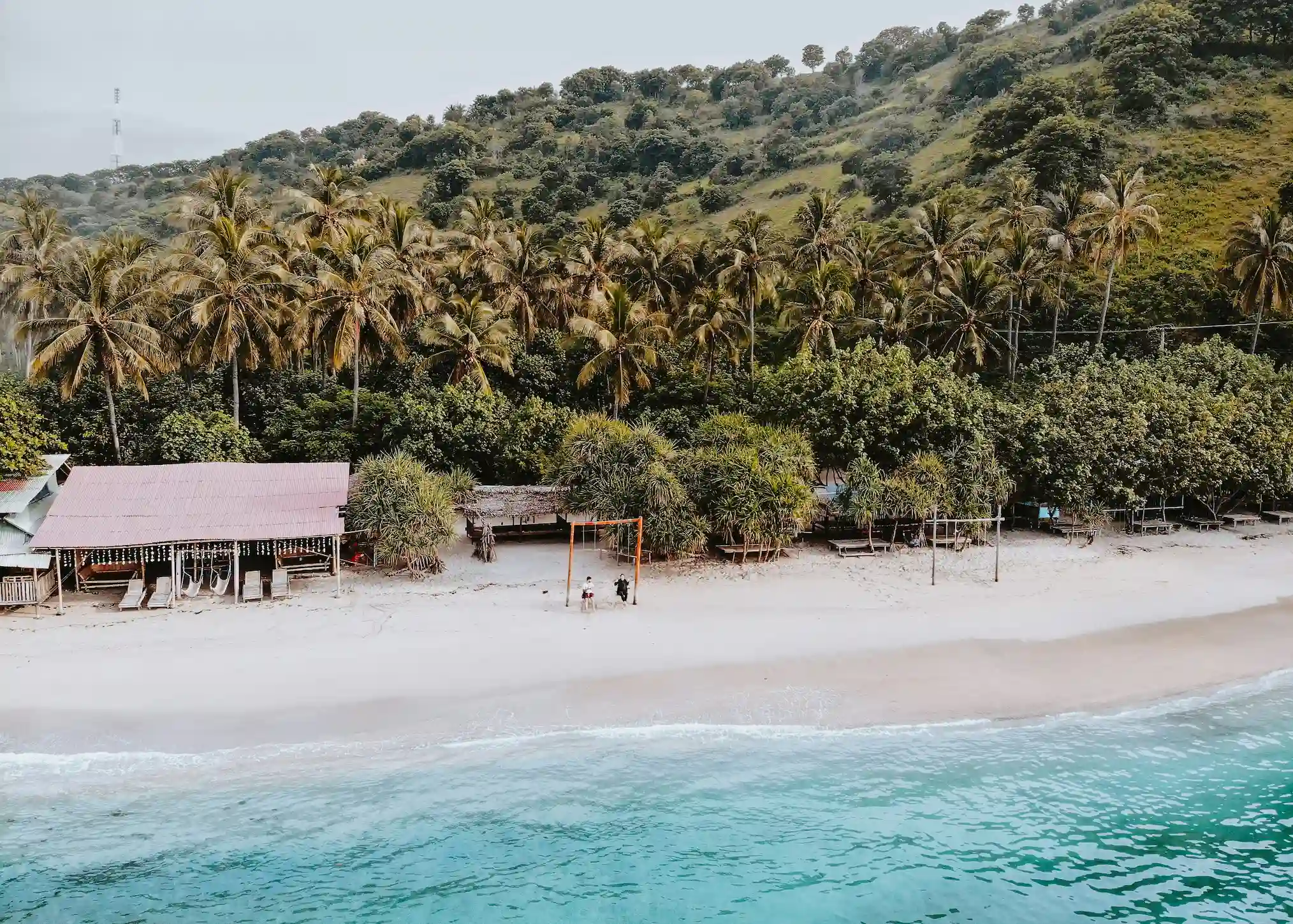 Plage paradisiaque, sable blanc et eau turquoise devant une jungle luxuriante et un couple sur une balancoire